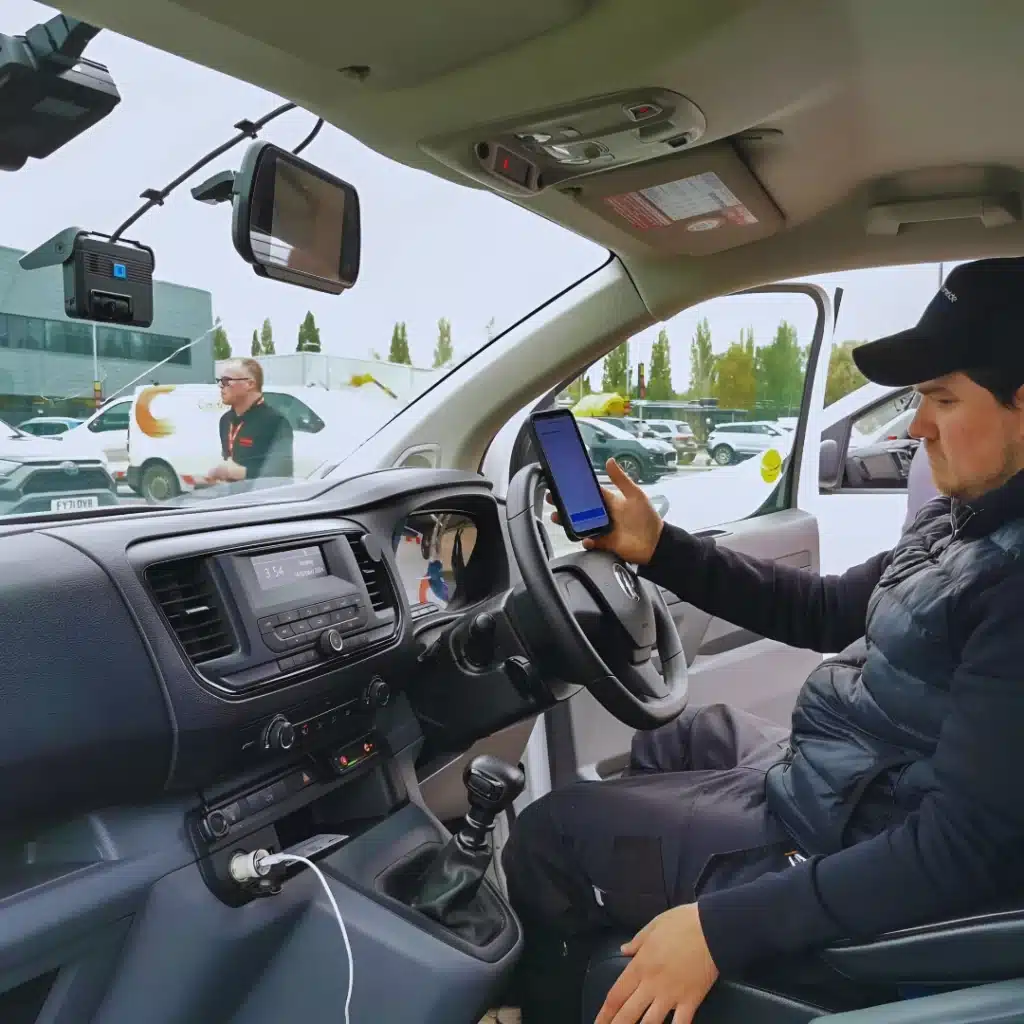 Nationwide Fleet Installations engineer inside a fleet van testing a driver-facing camera system using a mobile device.