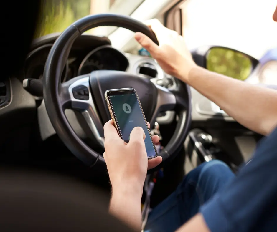 Driver using a mobile phone while driving, demonstrating dangerous and illegal behaviour