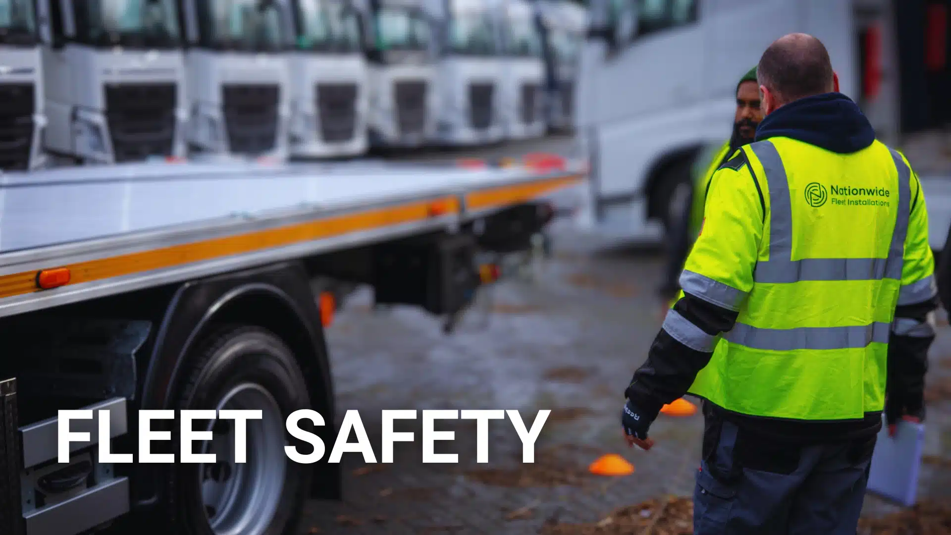 Nationwide Fleet Installations team member in high-vis jacket beside a line of commercial vehicles.