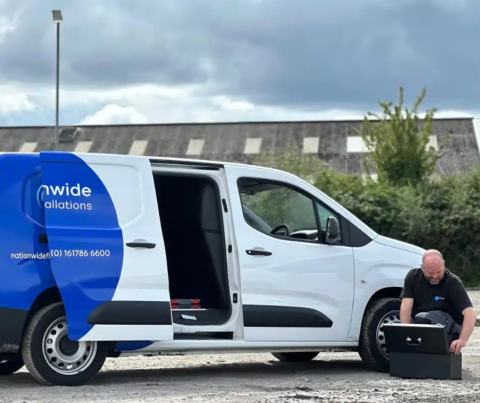 Nationwide Fleet Installations engineer preparing vehicle safety equipment beside branded van.