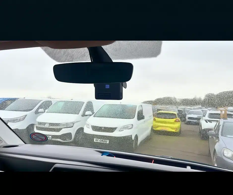 Rear-view image of a driver-facing camera installed in a fleet van, overlooking parked vehicles.