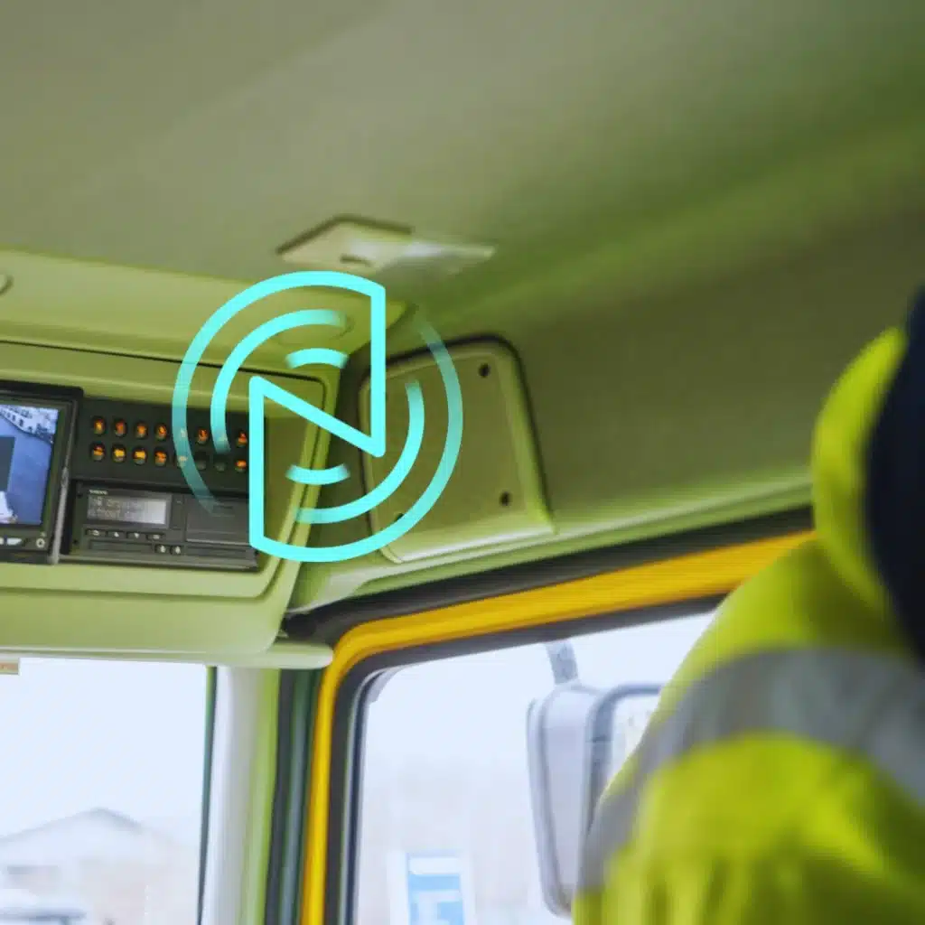 Engineer fitting remote tachograph download hardware inside a commercial vehicle cab.