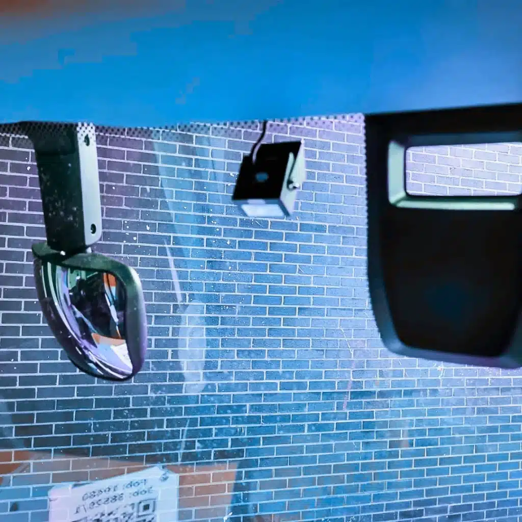 Interior view of a fleet vehicle showing a professionally installed forward-facing dash camera and internal sensor system.