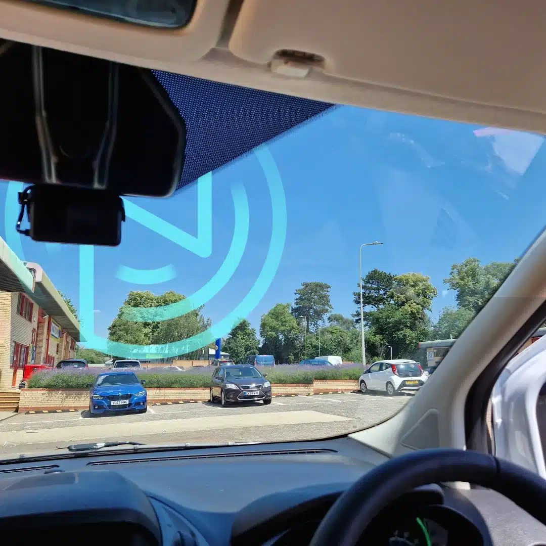Forward-facing camera installed on a van windscreen, capturing road data as part of a video telematics system.