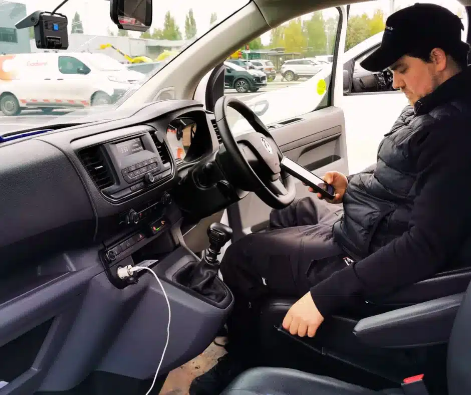 Technician testing and installing a fleet dash cam inside a commercial vehicle.